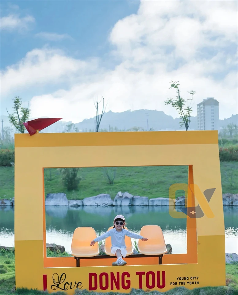 A yellow photo frame with three suspended seats and original city lettering.