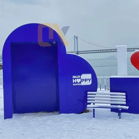 A blue heart-shaped backdrop with a bench in a snowy setting.