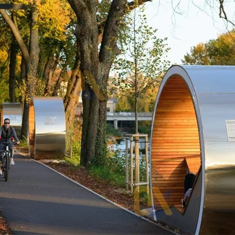 Cylindrical seating shelters beside a tree-lined path.