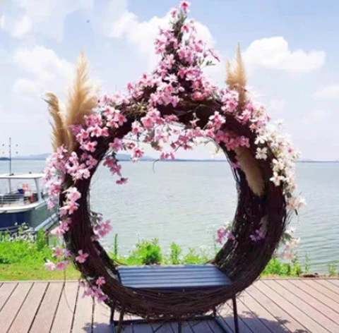 Woven nest seating with pink floral decorations on a waterside deck.