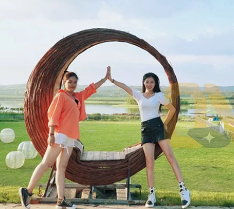 A circular woven seat on a lawn, with people showing its scale.